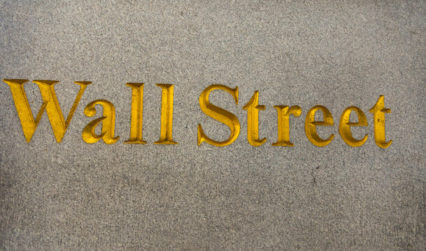 Wall Street inscription in gold lettering engraved on a granite stone surface