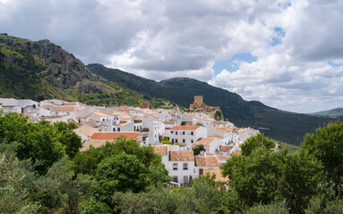 Obraz premium A breathtaking panoramic view of Zuheros, a historic village nestled in the hills of Córdoba, Spain. White-washed houses with terracotta roofs are surrounded by lush Mediterranean greenery under a dra