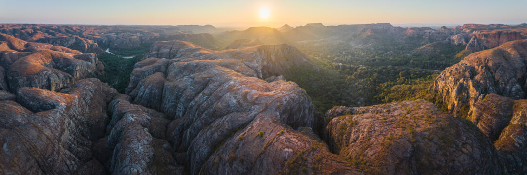 Aerial view of Makay massif with rugged sandstone formations, deep canyons, and lush vegetation under golden sunset light in Beroroha, Atsimo-Andrefana, Madagascar.