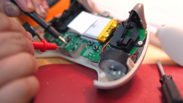 4K close-up footage of a technician diagnosing and repairing an electronic circuit board using a multimeter probe inside a handheld electronic device