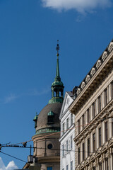 Obraz premium Historic European Building Featuring a Green Copper Dome and Classic Architectural Details Against Blue Sky