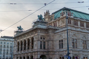 Obraz premium Majestic Vienna State Opera house featuring historic rooftop statues undergoing maintenance in the Austrian capital city