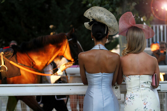 Dama pamela glamour mujeres elegancia belleza, clase y moda dos con sombrero en hip&oacute;dromo lujo p&uacute;blico de espaldas pareja espectadora Turf y caballo reflejo de lente y sol