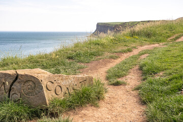 Naklejka premium The Cleveland Coast Path rock marker stands proudly on Saltburn's cliff top, with sweeping coastal views across the North Sea.