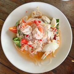 Spicy Glass Noodle Salad (Yum Woon Sen ). A vibrant seafood salad featuring plump shrimp,  vietnamese pork sausage, and glass noodles tossed in a zesty dressing, served on a clean white plate. © FTYCute