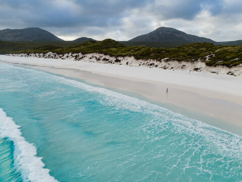 Aerial view of Hellfire Bay featuring turquoise water, white sand, and a person walking along the shore in Cape Le Grand National Park, Western Australia, Australia.