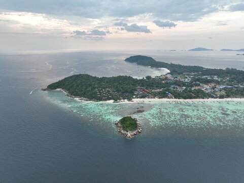 Aerial view of Koh Lipe island surrounded by turquoise waters, coral reefs, and lush greenery with a small islet in the foreground in Tambon Ko Tarutao, Chang Wat Satun, Thailand.