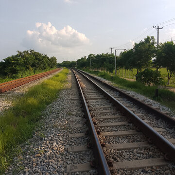 Railway Tracks Through Scenic Countryside Fields Under Open Sky with Long Perspective and Rural Landscape Travel Route