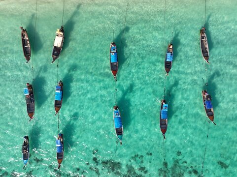 Aerial view of Koh Lipe Pier with traditional long-tail boats moored in clear turquoise water in Tambon Ko Tarutao, Chang Wat Satun, Thailand.