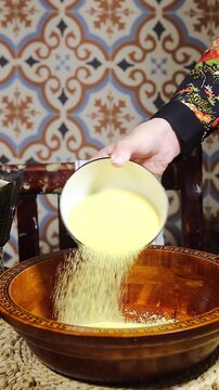 woman preparing an Algerian Couscous With Dried Fruit, Watermelon Slices and Milk on Patterned Tile Background
