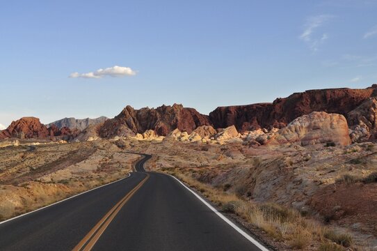 Small, winding road leads through red rocky landscape in the desert at sunset, Valley of Fire State Park, Nevada, USA