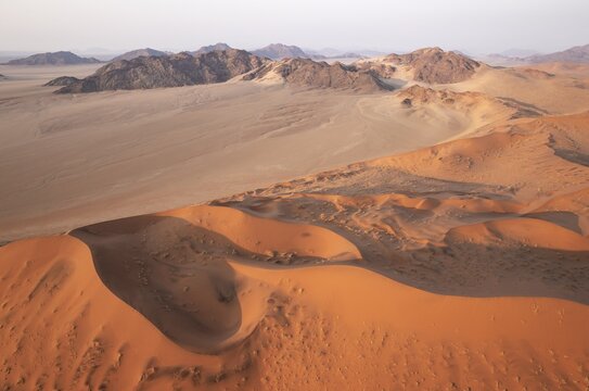 Sand dunes and mountain ridges in the Namib Desert. In the evening. Aerial view. Namib-Naukluft Park, Namibia