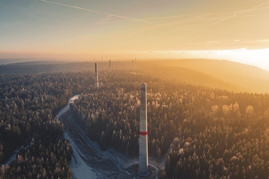 Sun rays over a foggy forest and wind turbine towers rising from the tree cover, Windkraft Bau, Besenfeld, Seewald, Freudenstadt district, Germany