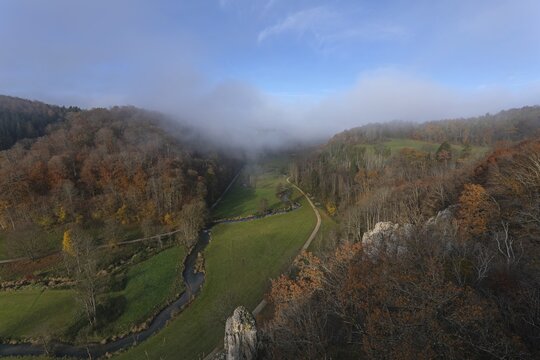 Autumn landscape with rising fog over the Grosse Lauter river loop in Lautertal at sunrise. View from above of the picturesque valley with colorful deciduous forest and rolling hills, Gro&szlig;es Lautertal, Baden-W&uuml;rttemberg, Germany