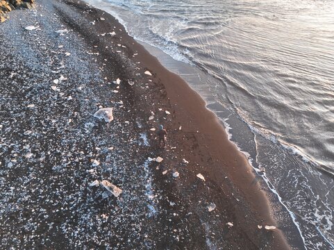 Aerial view of Diamond Beach with scattered ice chunks on the black sand shore and waves washing onto the coast in Hofn, Sveitarfelagid Hornaf, Iceland.