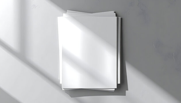 Top view of stack of blank white paper sheets casting hard sunlight shadows on dark grey textured surface