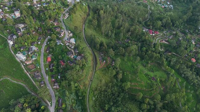 Cinematic morning drone flight over lush tea estates, scattered houses, dense trees, and a railway track surrounded by vibrant greenery &ndash; peaceful tropical landscape aerial footage | Haputale, Sri Lan