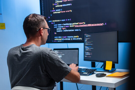 Male Software Developer Working at a Computer While Writing Code for an AI Application and Reviewing Program Logic in a Modern Office. Working on Programming Tasks for Cybersecurity Systems and Secure