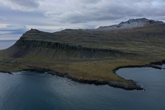 Aerial view of Hafnarnes Lighthouse and viewpoint on the rugged coastline with dramatic cliffs, dark volcanic terrain, and the Atlantic Ocean in Thorlakshofn, Sveitarfelagid Olfus, Iceland.