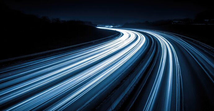 Streaks of light trace a nighttime highway's curving path under the moon