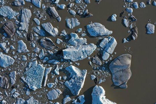 Aerial view of Svinafellsjokull Glacier with floating icebergs and chunks of glacial ice drifting in the dark meltwater lake in Svinafell, Sveitarfelagid Hornaf, Iceland.