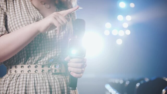 Stylish Female Event Host Holding Microphone on Professional Stage