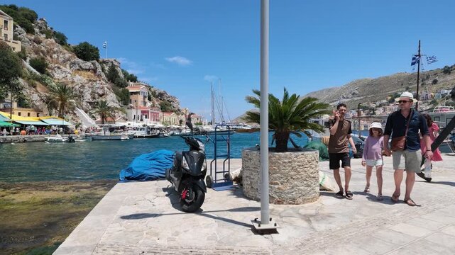 SYMI, GREECE - JUNE 5, 2026: Tourists walking through the colorful streets and harbor of Symi island during a sunny day