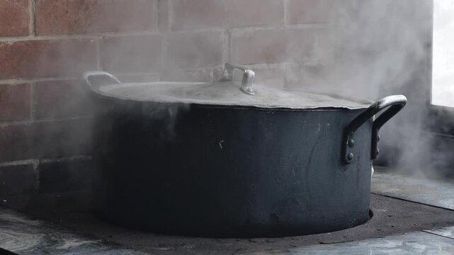 Traditional cooking pot steaming on old wood stove in a rustic kitchen