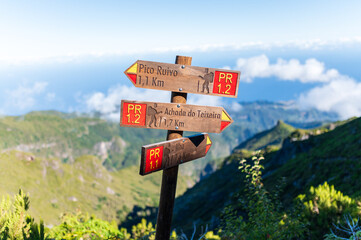 Wooden trail signpost pointing to Pico Ruivo and Achada do Teixeira in the mountains of Madeira island © mathias.elle