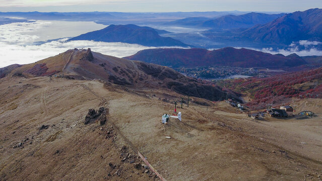 Aerial view of the rugged mountain terrain of Cerro Catedral with ski infrastructure, rocky slopes, and autumn foliage in San Carlos de Bariloche, Rio Negro Province, Argentina.