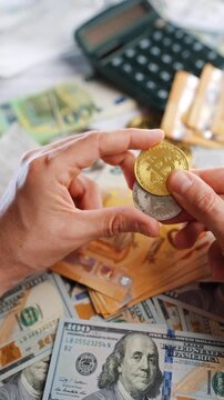 Hands shows silver and golden BTC bitcoin against the dollars and euros