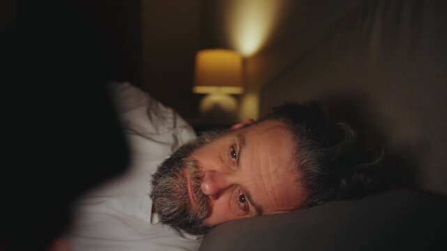 A man lying in bed using smartphone late at night
