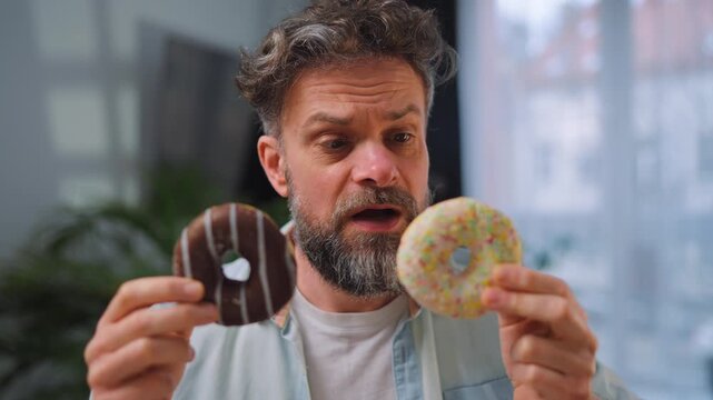 A man eating two donuts simultaneously with delight. Sugar addiction. Slow