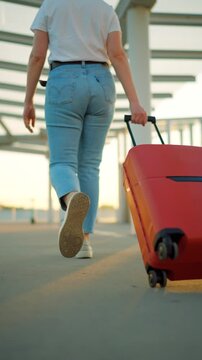 Woman confidently pulling a suitcase in an airport terminal. Back view