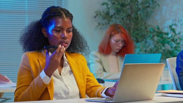 Black female business analyst using AI agent on laptop for strategic planning at night office, artificial intelligence assistant helping corporate decision making, future of work concept