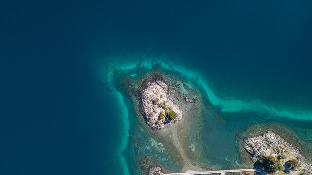 Aerial view of a small rocky island with sparse vegetation surrounded by turquoise water in Nahuel Huapi Lake, San Carlos de Bariloche, Rio Negro Province, Argentina.