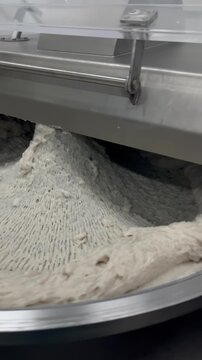 High-capacity bowl cutter mixing meat ingredients in a food manufacturing facility. Industrial chopping and blending process supporting processed meat production, food consistency, and large-scale man
