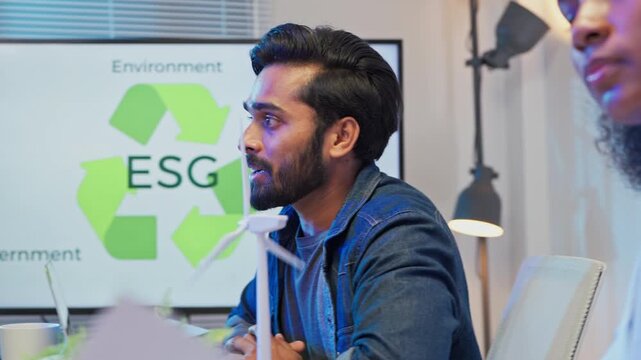 Diverse multiracial business team sitting in night office presenting ESG restructuring plan for clean energy profit growth, corporate consulting analysts strategy meeting concept
