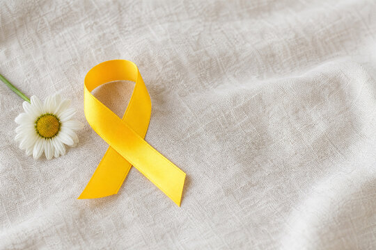Yellow awareness ribbon with white flower on linen fabric, symbol of hope and mental health support.