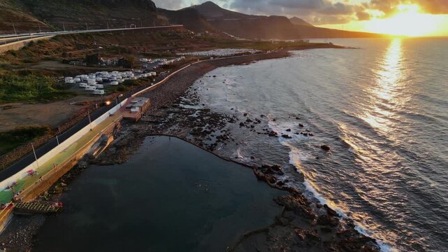 Beautiful aerial view of San Andres Beach, natural pools in Arucas, Gran Canaria, at sunset. The Atlantic Ocean waves crashing against the rocky coast