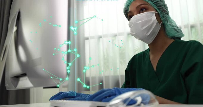 Female Asian doctor in green scrubs, surgical mask, and cap types on a computer with abstract medical data graphics, showcasing futuristic healthcare technology and digital research