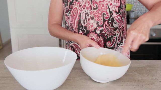 Close up of organic eggs being whisked in deep white bowl while making homemade apple cake, preparing fresh healthy ingredients for sweet nutritious dessert, culinary cooking process in home kitchen