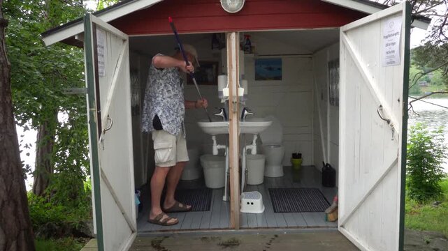 Stockholm, Sweden A man mops and cleans a public latrine in a campground.