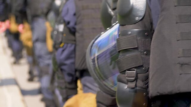Police units align to ensure security at public rally. Dressed elbow pads and uniforms. Peaceful crowd control during public demonstration. Law enforcement officers