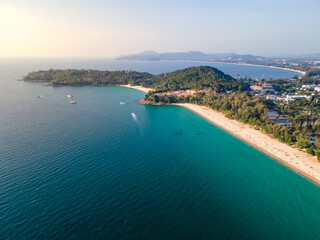 Fototapeta premium Aerial top view of Surin beach and Pansea Beach during sunset. Turquoise waves reach the Andaman sea coastline on a sunny day. Travel attractions for summer vacation in Phuket, Thailand.