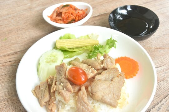 fried slice pork with teriyaki sauce and salad with kimchi tpping plain rice on plate