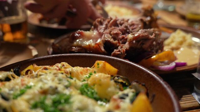 Czech restaurant meal features pork knuckle sliced by hand and baked potatoes with melted cheese.