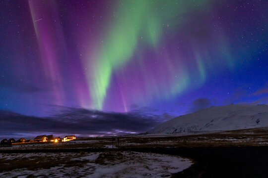 Colorful northern lights over snowy landscape and mountain in Iceland