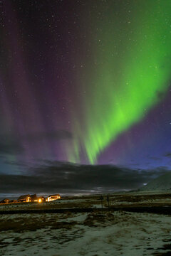 Northern lights above rural Icelandic landscape and mountain at night