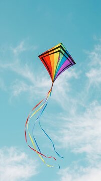 Colorful rainbow kite flying against clear blue sky 